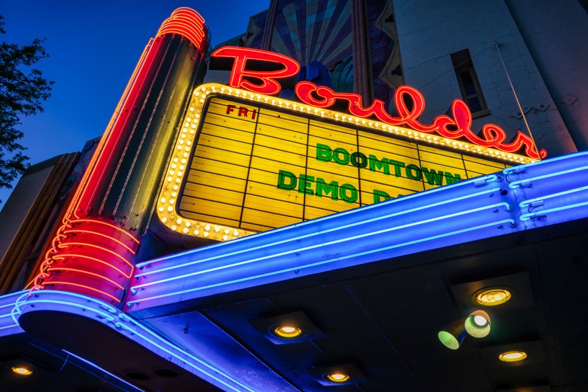 Neon-lit marquee of the Boulder Theater viewed from below against a deep blue evening sky.