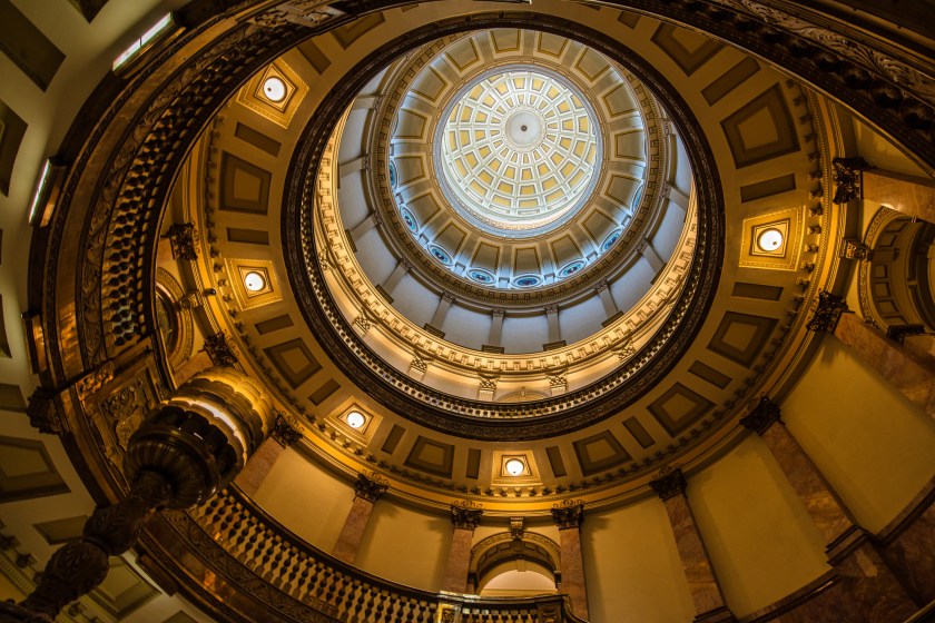 Upward view of the ornate rotunda ceiling inside the Colorado State Capitol, showing concentric arches and a central skylight.