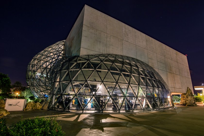 Nighttime long exposure photograph of the Dali Museum in St. Petersburg, Florida, showing its illuminated geodesic glass structure and concrete facade.