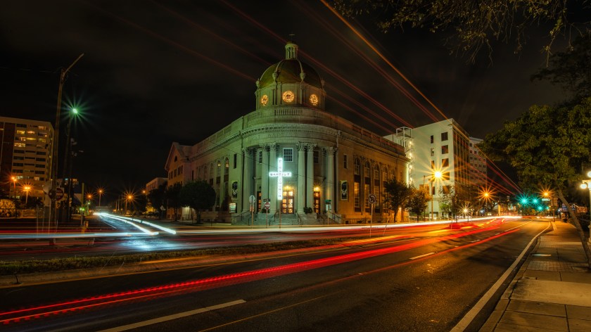 Long exposure nighttime photograph of the historic First Baptist Church in Tampa, Florida, with vehicle light trails in the foreground.