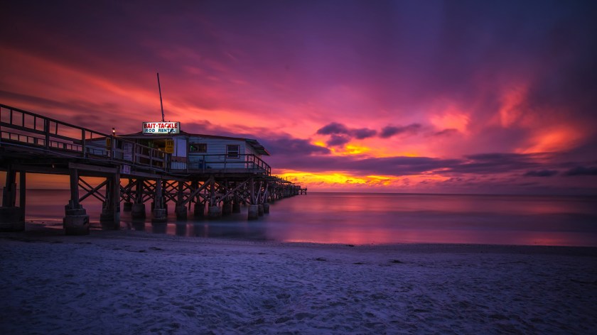Long exposure photograph of the Redington Long Pier on Redington Beach, Florida, taken after sunset with vivid sky colors and calm reflective water.