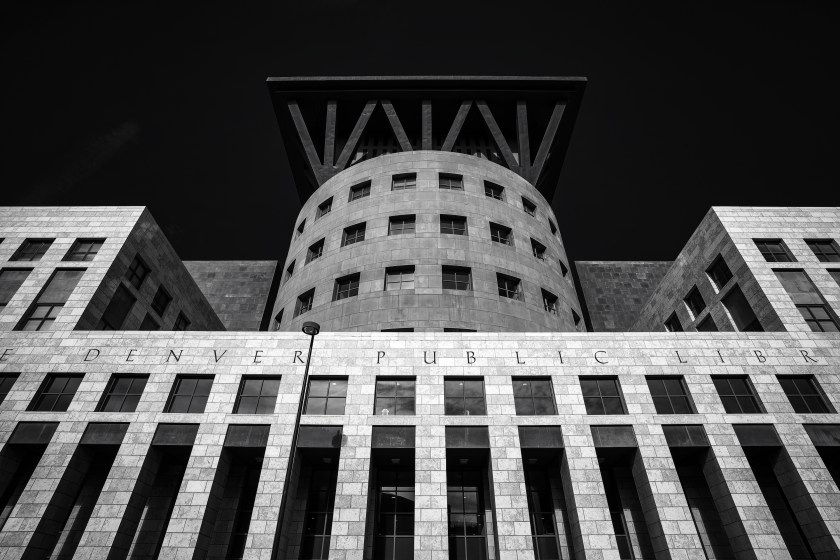 Black and white view of the Denver Public Library exterior, showing a cylindrical central structure framed by angular stone façades.